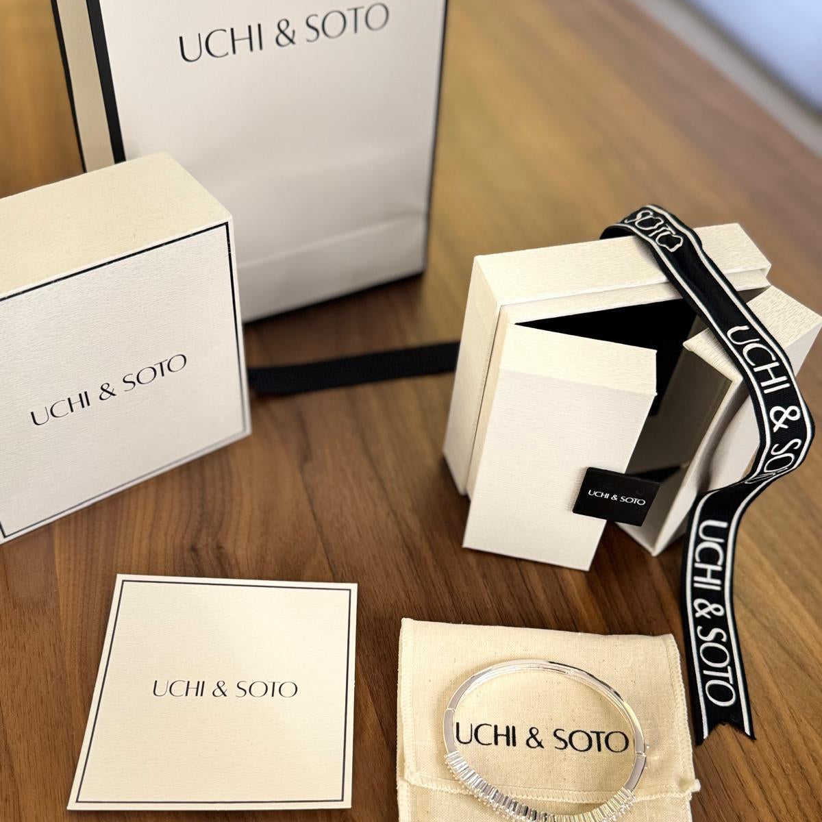 Uchi & Soto jewelry set with packaging on a wooden surface