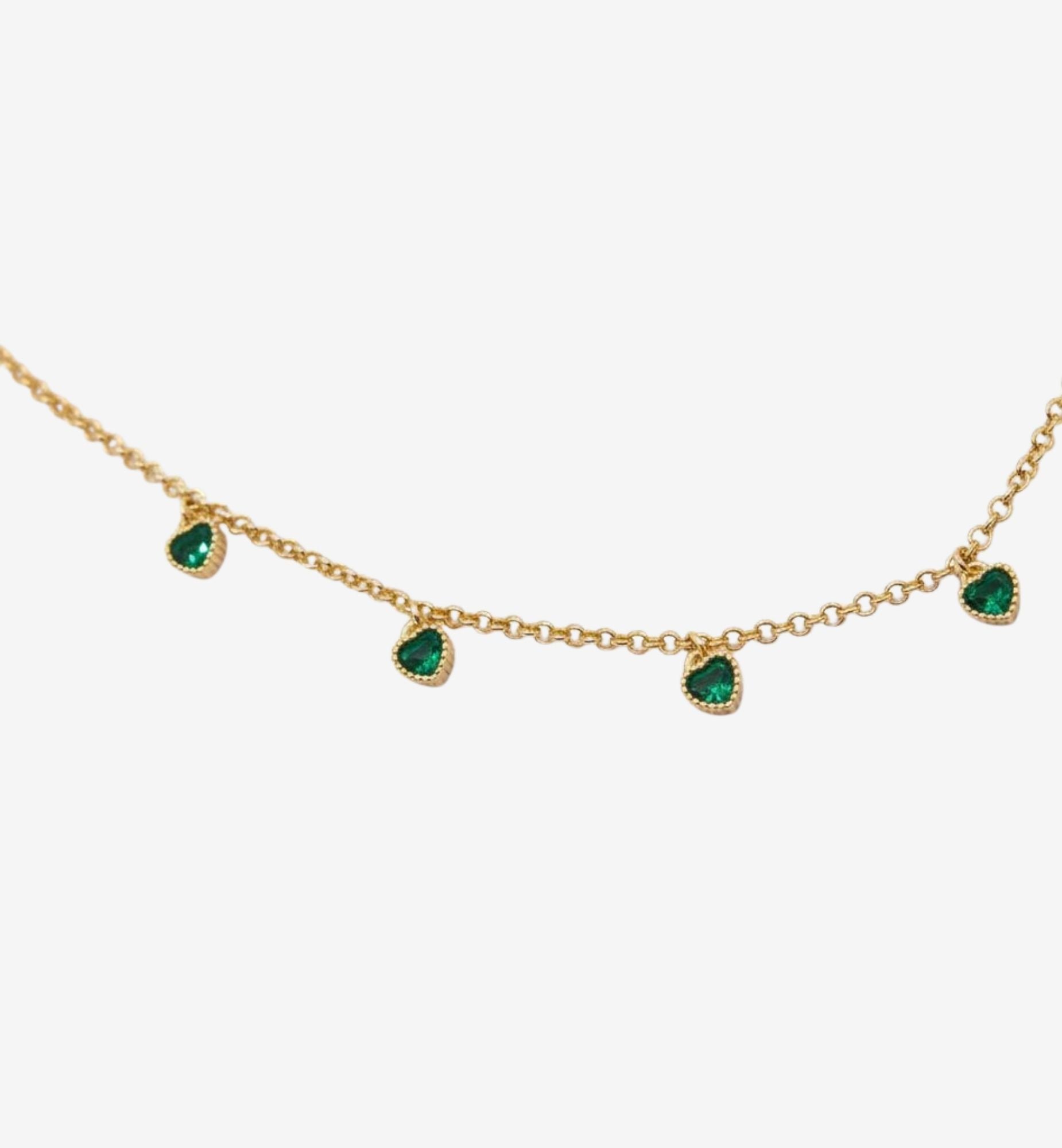 Gold necklace with emerald green gemstones on a white background