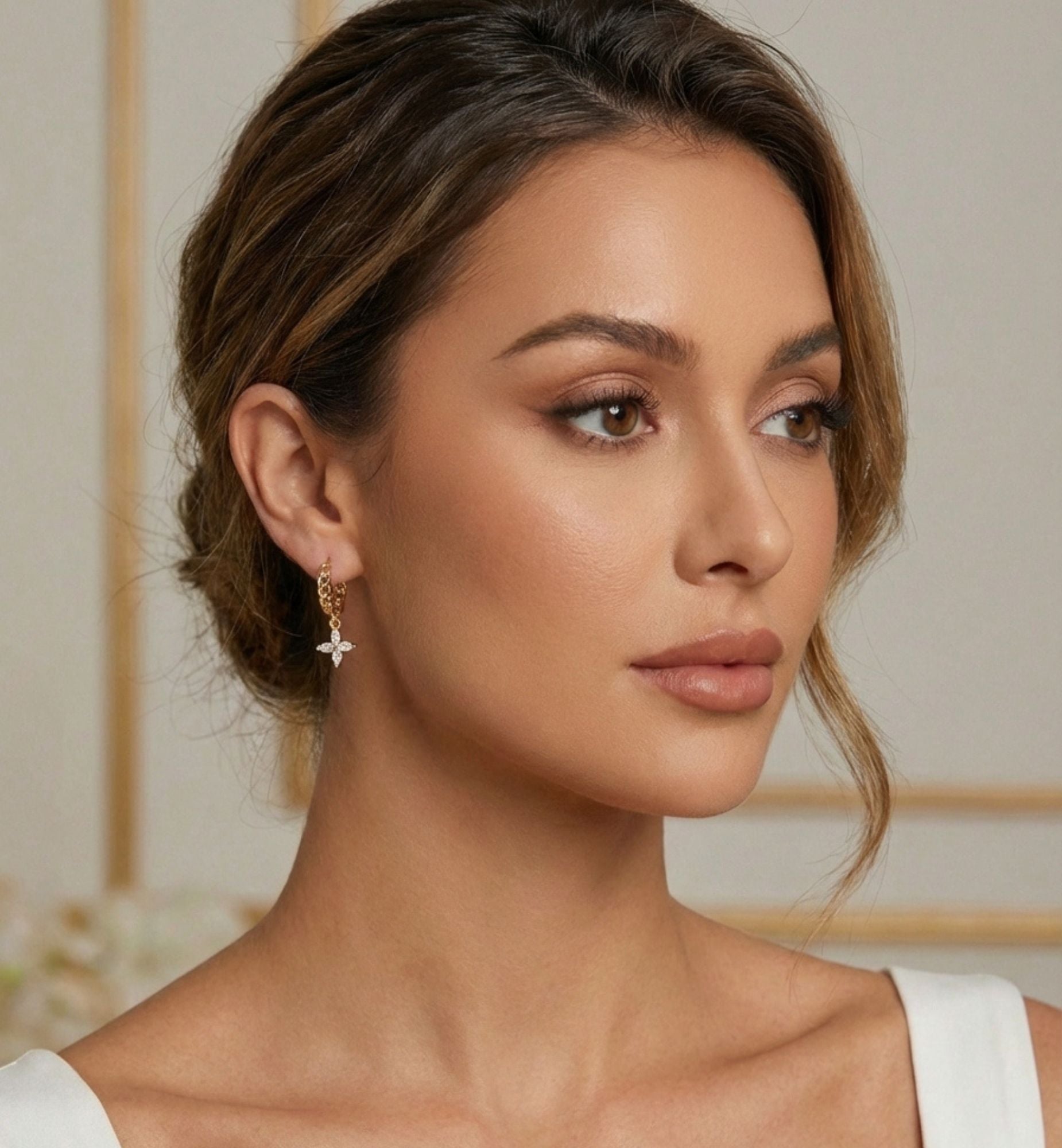 Woman wearing a white top with a blurred background with flower earrings