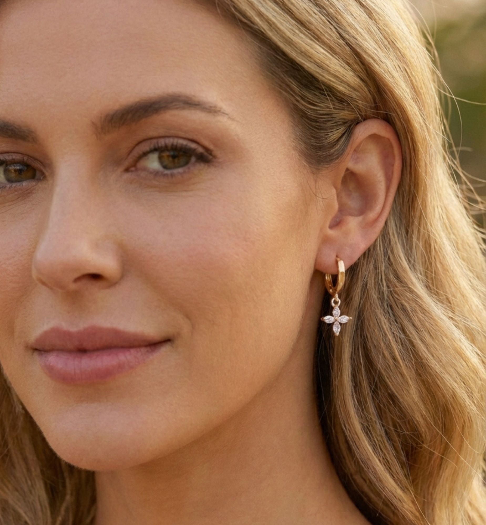 Close-up of a woman wearing a delicate earring with a blurred natural background