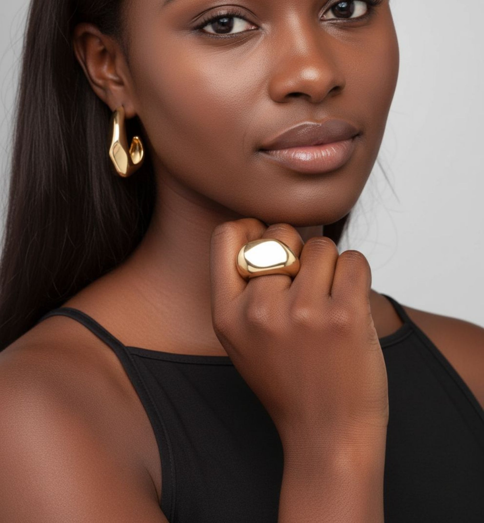 Woman wearing gold jewelry against a neutral background