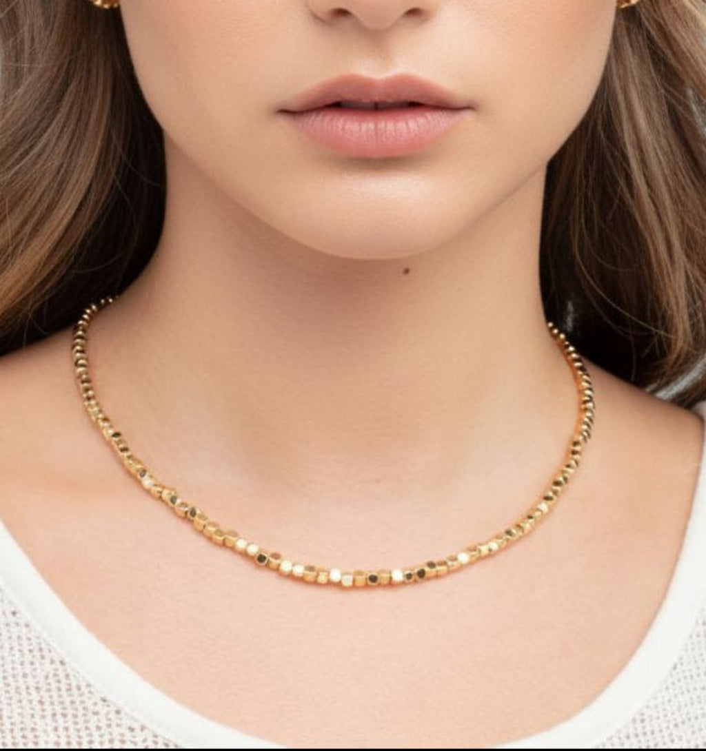 Close-up of a person wearing a gold necklace with a blurred background