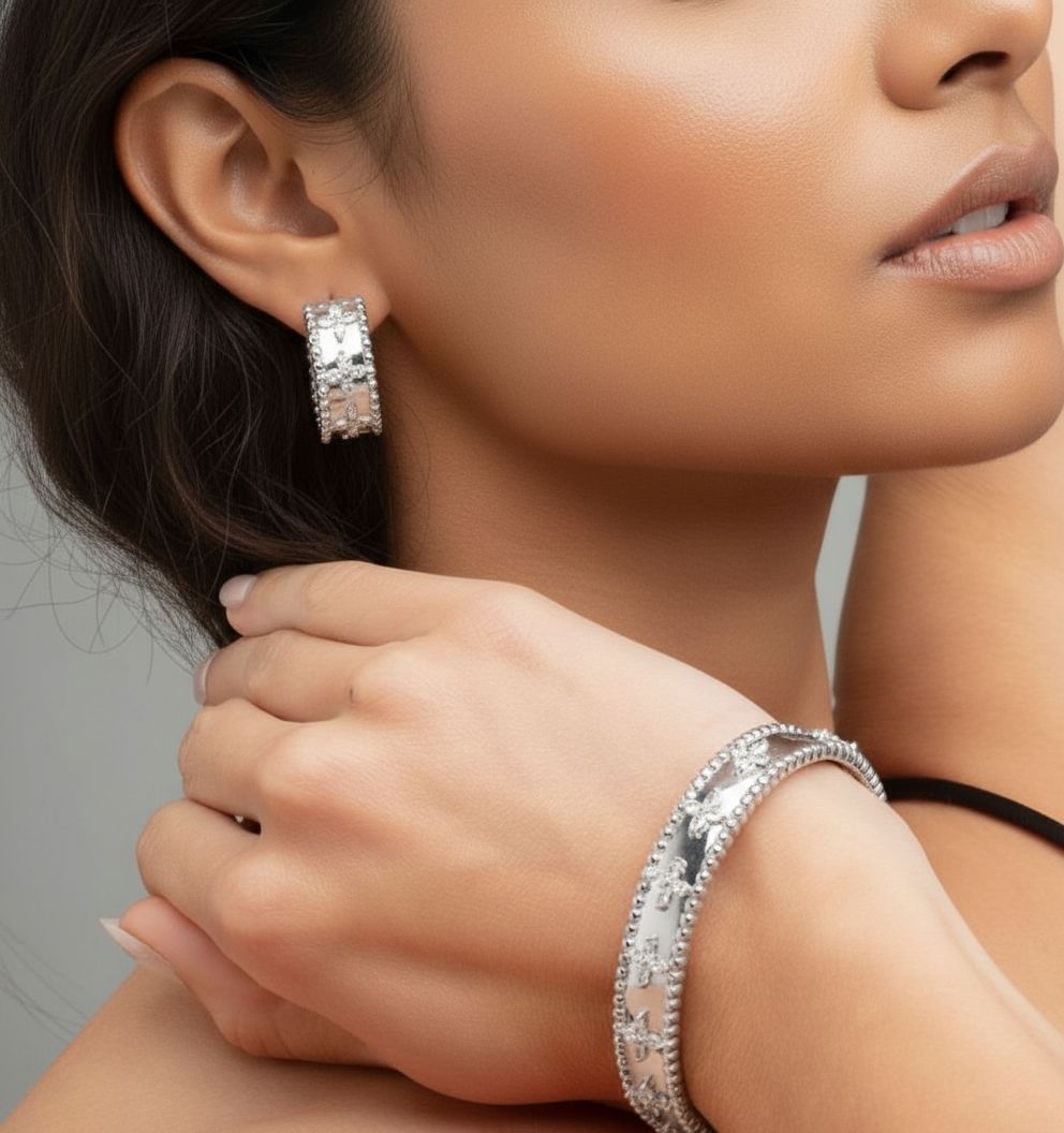 Close-up of a woman wearing silver hoop earrings and bracelet on a neutral background