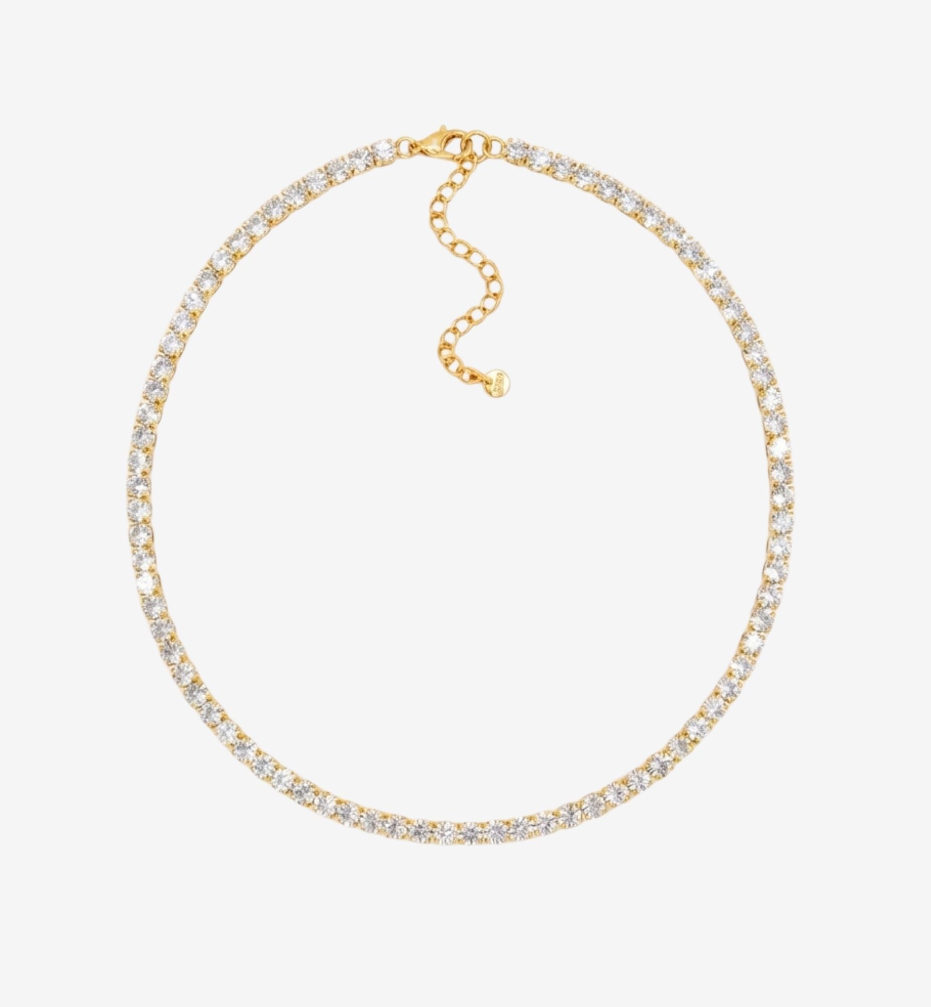 Gold necklace with clear stones on a light gray background