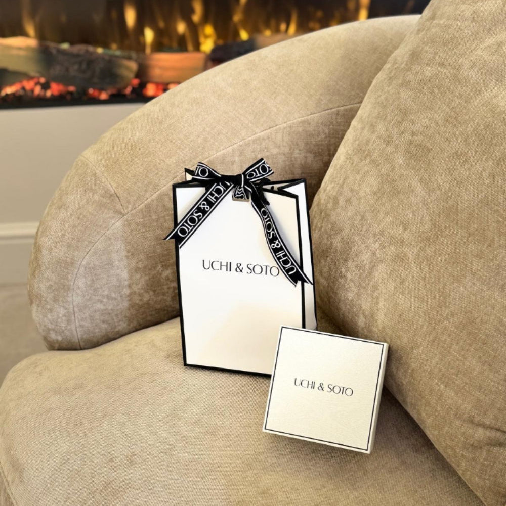 Uchi & Soto product packaging on a beige sofa with a fireplace in the background