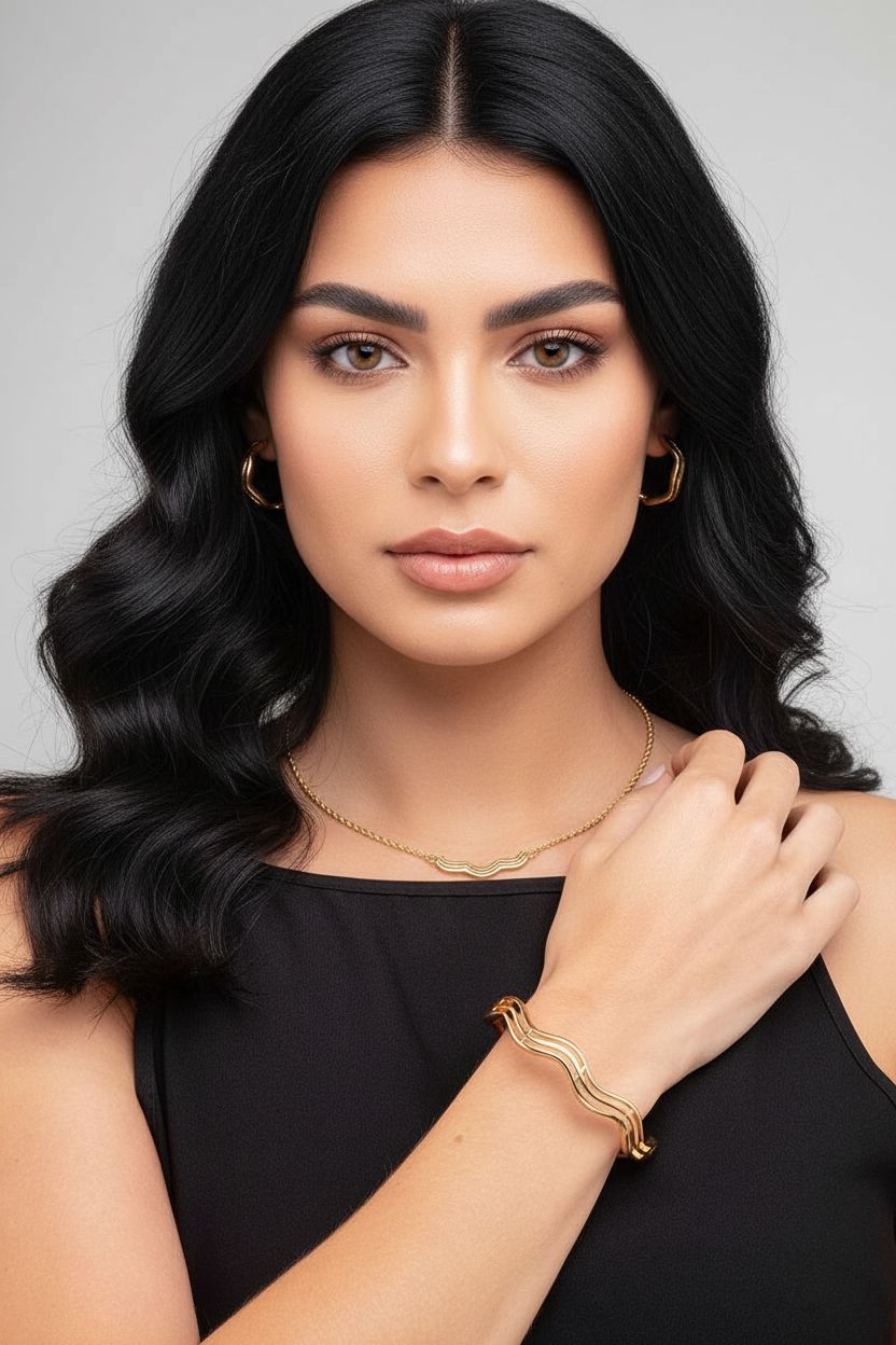 Woman with black hair and gold jewelry against a gray background