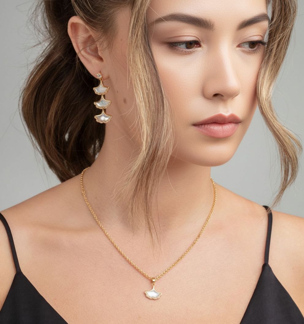 Woman wearing a gold necklace and earrings with a neutral background