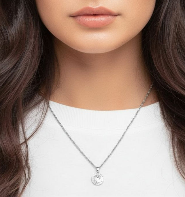 Woman with long, wavy hair wearing a necklace against a neutral background