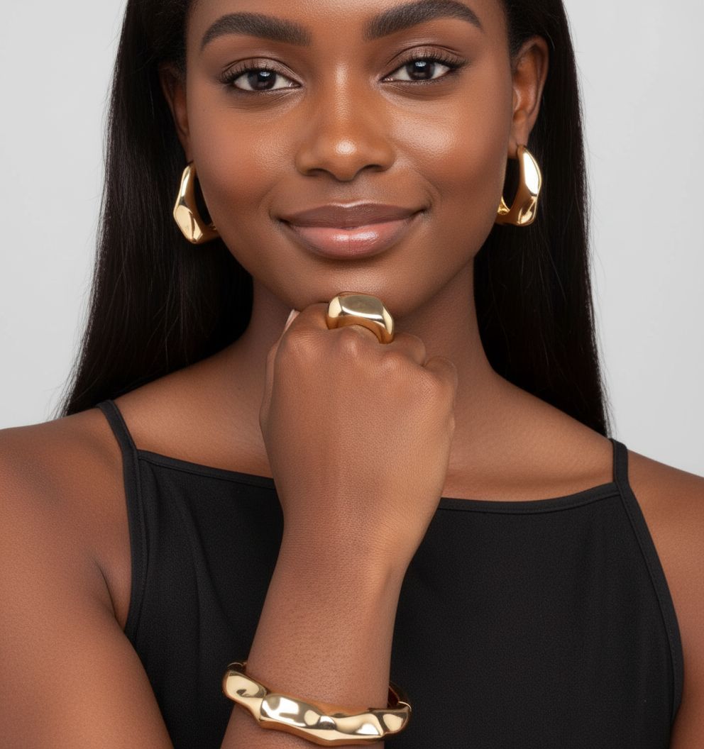 Woman wearing gold jewelry including earrings and a ring, with a plain background